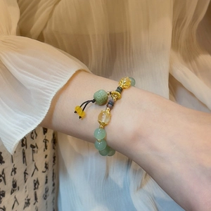 Detail of beaded agate bracelet with golden hollow charms and adjustable black cord