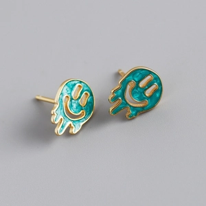Macro detail of gold melting smiley face earrings with teal blue oil drip finish