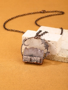 Detailed shot of moon and star copper pendant with a translucent purple crystal stone