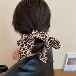 Détail d'un ruban en satin imprimé léopard noué sur le chignon bas d'un mannequin
