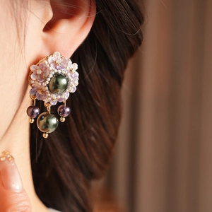 Detail of vintage floral resin earrings with purple petals and green pearl tassels