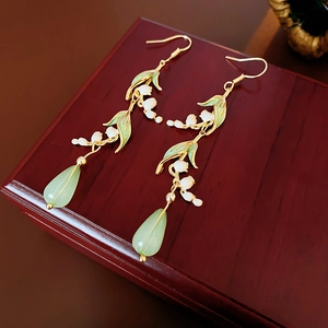 Macro view of Lily of the Valley drop earrings with green enamel leaves and resin beads