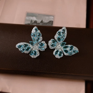 Detailed close-up of butterfly earrings with blue pear-shaped stones and white crystals