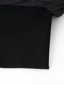 Close-up detail of high-quality black ribbed knit cuffs on a short puffer jacket