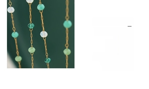 Detailed macro view of faceted green crystal beads and gold chain on tulip pendant necklace