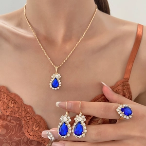 Chic gold jewelry set with blue pear-cut rhinestones worn by a model in lace attire