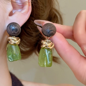 Détail de boucles d'oreilles en résine avec perle de bois et métal doré