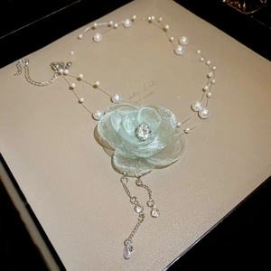 Detail of light green lace flower necklace with pearls in a beige velvet jewelry box