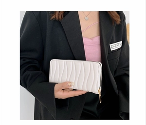 Close-up of white PU long wallet with wave pleated texture and gold zipper detail