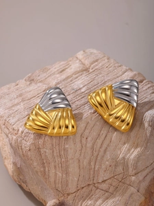 Macro detail of geometric triangle earrings with ribbed texture and two-tone gold finish