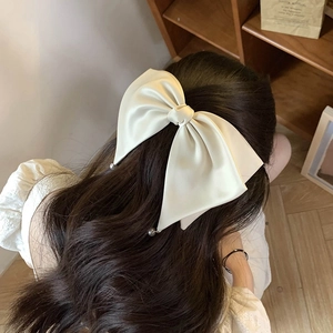 Close-up of cream satin bow hair clip with pearl beads on French style ribbons