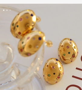 Macro shot of oval gold earrings with colorful crystals against a vintage background
