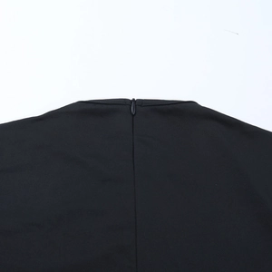 Detailed close-up of the invisible rear zipper and black woven fabric of the jumpsuit