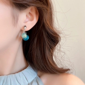Primo piano di una modella che indossa orecchini d'argento con perline blu e verdi trasparenti