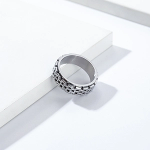 Macro shot of silver titanium steel spinner ring with 3D checkered texture on white stand