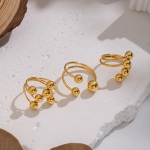 Three gold stainless steel stackable geometric bead rings on a white stone background