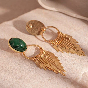Macro shot of vintage gold earrings with green oval stone and metallic fringe detail