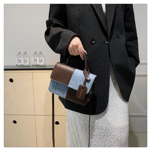 Detail view of square patchwork bag in brown leather and denim blue with fashion tag