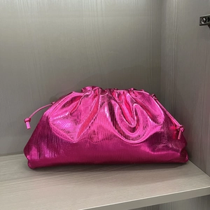 Detail view of fuchsia cloud clutch with metallic pleated texture and side knot ties