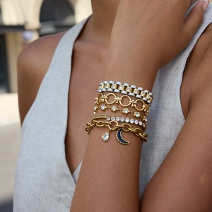 Close-up of layered 18K gold and silver stainless steel bracelets with moon pendants