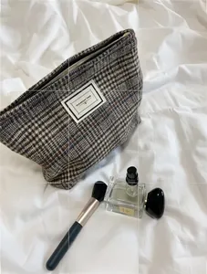 Detailed view of checkered tweed makeup bag with zipper and Pleasant Time label