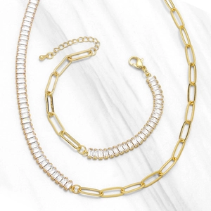 Golden necklace and bracelet set featuring zircon gems and paperclip links on marble