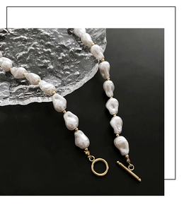 Detailed macro view of baroque pearl necklace with gold toggle clasp and metallic beads