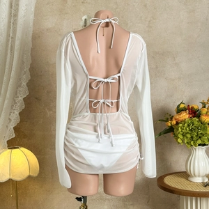 Detail of white mesh beach cover-up featuring open back and elegant ribbon tie bows
