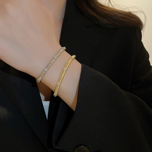 Detail of gold and silver plated brushed metal cuffs with zircon stones on model's wrist