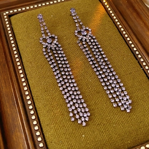 Détail de boucles d'oreilles à aiguille en argent, strass violets et pompons multicouches