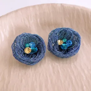 Deep blue woven wire flower earrings with multi-color rhinestones on a beige ceramic tray
