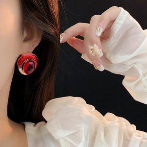 Close-up of vintage gold oval earrings with red enamel and crystals on a model