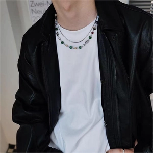 Detail of layered silver snake chain and colorful beaded necklace on male model