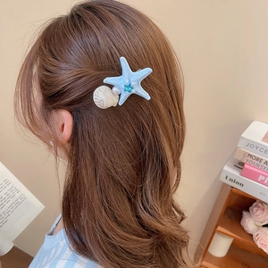 Detail of starfish and seashell hair clip with pearls and blue rhinestones on hair