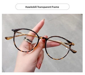 Detail of round tortoiseshell frames with slim gold metal temples and clear lenses
