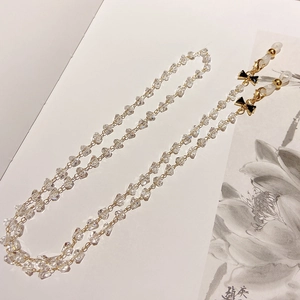 Close-up of crystal eyeglass chain with black bow decoration and gold metal lobster clasp