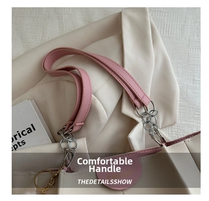 Dettaglio del manico in pelle rosa e della catena in metallo su una borsa beige