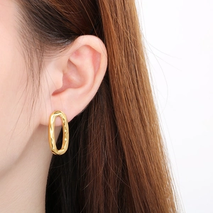 Detail of gold oval teardrop earrings with irregular molten texture on model