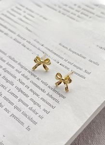 Detailed view of elegant gold bow stud earrings placed on a vintage book background