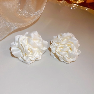 Dettaglio ravvicinato di eleganti orecchini a lobo a forma di rosa in tessuto bianco crema