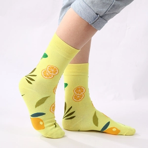 Macro detail of yellow cotton crew socks featuring bright orange and leaf patterns