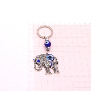 Detailed size view of silver elephant evil eye keychain on red scale grid paper