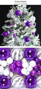 Dettaglio di palline di Natale viola e bianche con glitter e strisce su rami innevati