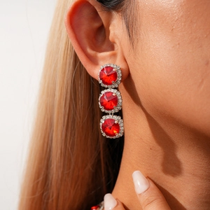 Close-up of triple red crystal drop earrings with sparkling pavé border on a model