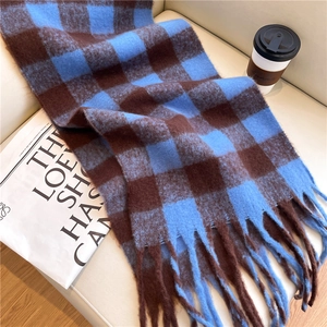 Detail of soft winter scarf with blue and brown plaid patterns and long fringe tassels