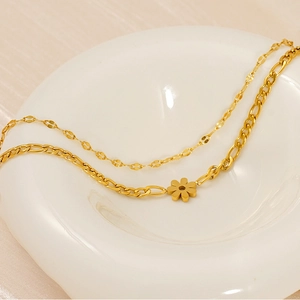 Detail of 18K gold double-layer necklace featuring a sunflower pendant on white ceramic