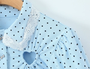 Detail of light blue polka dot romper with lace collar and heart cutout design