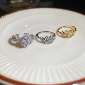 Detailed close-up of zircon clover rings and purple gemstone ring on white ceramic plate