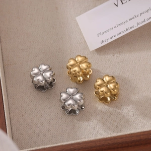 Golden and silver four-leaf clover charms on a linen cloth background for jewelry making