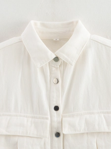 Detail of white cotton shirt vest featuring metal buttons and symmetrical chest pockets